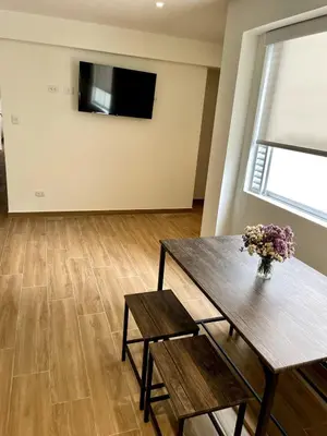 a living room with a table and a vase of flowers at Departamento in Magdalena del Mar in Lima