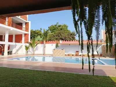 a swimming pool in a resort with a palm tree at Oliver's Garden Country Hotel in Chincha
