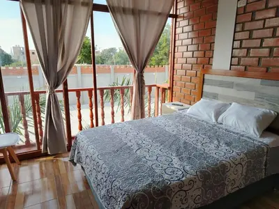 a bedroom with a bed and a large window at Oliver's Garden Country Hotel in Chincha
