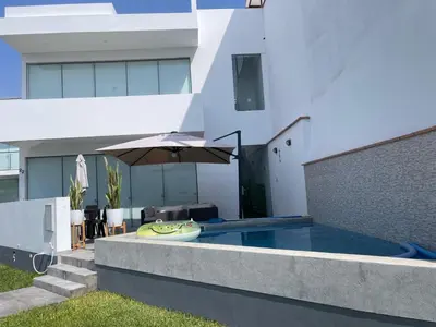 a house with an umbrella and a swimming pool at Hermosa casa de playa Asia in Lima
