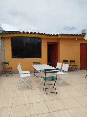 a patio with a table and chairs and a building at Apart Hotel Valdelomar in Ayacucho
