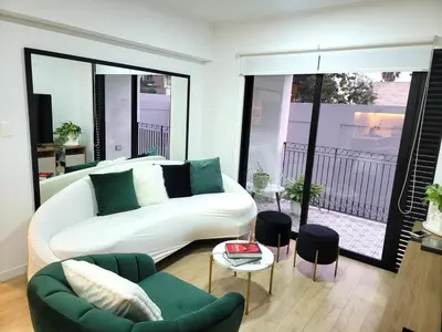 a living room with a white couch and green chairs at Bello y amplio apartamento, en la mejor zona de Barranco in Lima