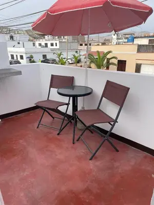a table and two chairs and an umbrella on a roof at Lindo departamento muy cerca a la playa in Punta Negra
