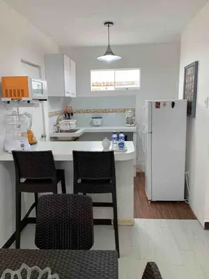 a kitchen with a white refrigerator and two chairs at Mini Dpto frente al mar playa Pta N in Punta Negra