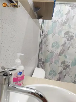 a bathroom with a sink and a bottle of soap at Atenas Backpacker Hospedaje in Paracas