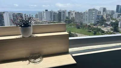 a vase on a window sill with a view of a city at Inca inn apartments in Lima