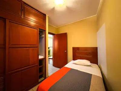 a small bedroom with a bed and a wooden cabinet at Apart-Hotel El Cañaveral in Chincha
