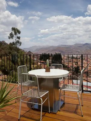 a table and chairs on a deck with a view at Casa Campestre on the side of Saqsaywaman in Cusco