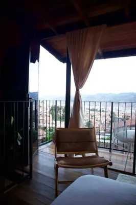 a room with a bed and a chair on a balcony at Mountain lodge with Spectacular View in Cusco