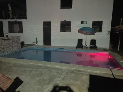 a swimming pool with an umbrella and two chairs at Chinchacampoymar Casa de playa en Chincha in Chincha Baja