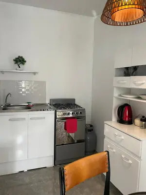 a kitchen with a stove and white cabinets and a chair at Departamento mejor sector de Ica in Ica