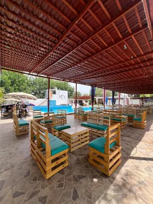 a patio with wooden chairs and tables and a pool at Hotel Los Pecanos in Ica