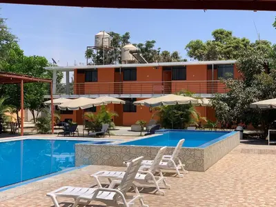 a hotel with a pool and chairs and a building at Hotel Los Pecanos in Ica