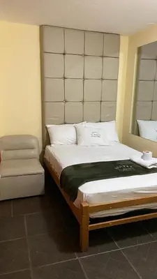 a bedroom with a large bed and a chair at Hostal El Bosque in Huánuco