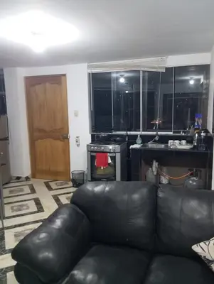 a living room with a leather couch and a kitchen at Apartamento con vista espectacular al Valle Sagrado de los Incas in Urubamba