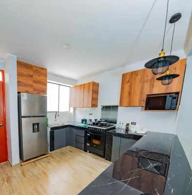 a kitchen with stainless steel appliances and wooden cabinets at La covacha de viejo in Jauja