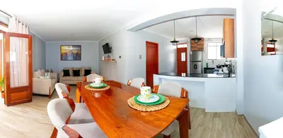 a dining room and kitchen with a wooden table and chairs at La covacha de viejo in Jauja