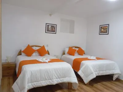 a bedroom with two beds with orange and white sheets at La casa de Goya in Cusco