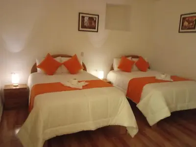 a bedroom with two beds with orange and white sheets at La casa de Goya in Cusco