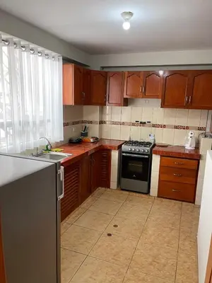 a kitchen with wooden cabinets and a stove top oven at La esquina de vallecito in Cusco