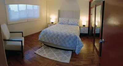 a bedroom with a bed and a window and a chair at La Palmera in Lima