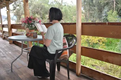 a woman sitting at a table reading a book at Pisonaywasi - Hospedaje familiar in Urubamba