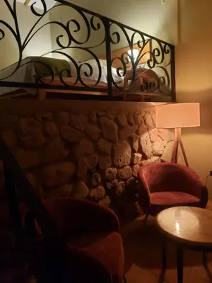 a room with a stone wall with a chair and a lamp at Casa de La Chola in Ollantaytambo