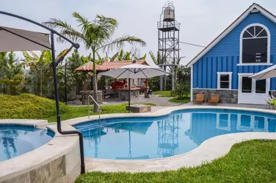 a swimming pool in front of a blue house at Villa Aurora in Aucallama