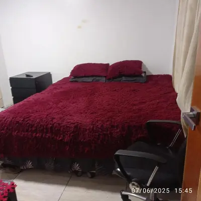a bedroom with a bed with a red comforter and a chair at Colibri in Lima