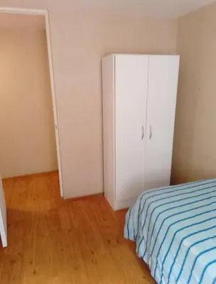 a bedroom with a white cabinet and a bed at Alquilo Departamento en Comas in Lima