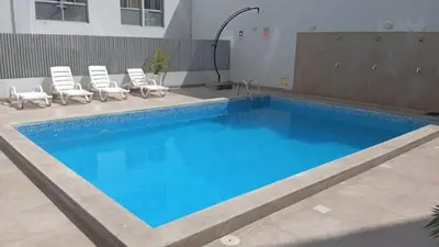 a swimming pool with lounge chairs next to a building at Departamento con piscina ubicado en Breña in Lima