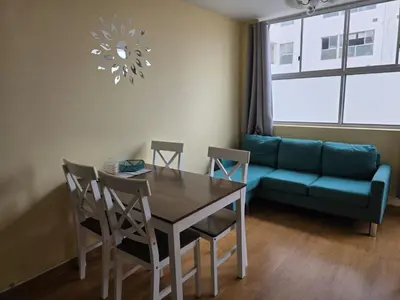 a living room with a table and a couch at Departamento con piscina ubicado en Breña in Lima