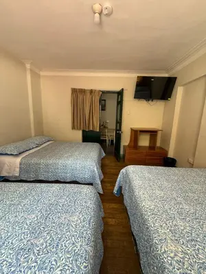 a hotel room with two beds and a television at Hospedaje Casa de Liz Cusco in Cusco