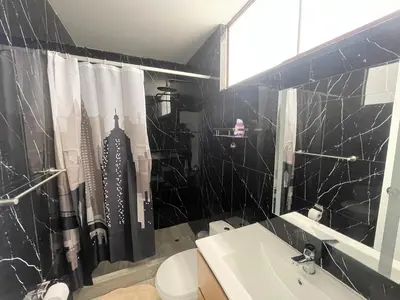 a bathroom with a black tiled shower curtain and a sink at Casa de campo en condo cerca a playa Puerto Viejo in San Antonio