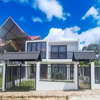 a white house with black gates and a fence at Casa Qiru tu Refugio en Oxapampa in Oxapampa