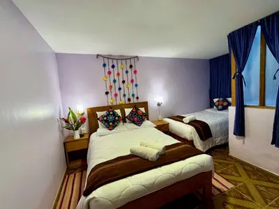 a bedroom with two beds in a room with purple walls at Tika house in Cusco