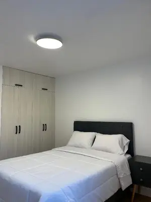 a bedroom with a large white bed and a cabinet at Habitaciones casa Bella in Lima