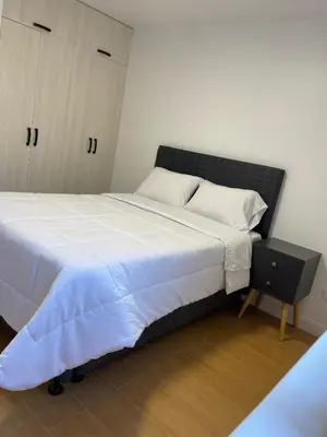a bedroom with a large bed and a night stand at Habitaciones casa Bella in Lima