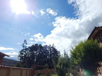 a blue sky with clouds and trees in a yard at Casa Higospampa, 2 Floors Up to 7 Residents in Urubamba
