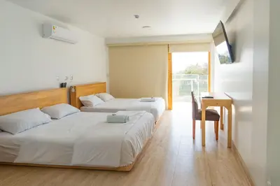 two beds in a hotel room with a desk and a desk at Hotel Boutique La Angostura II in Ica