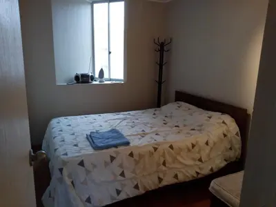 a bedroom with a bed with a white comforter and a window at Claudio in Lima