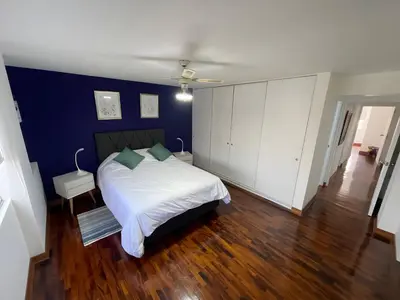 a bedroom with a white bed and a blue wall at Dpto Benavides la paz miraflores in Lima