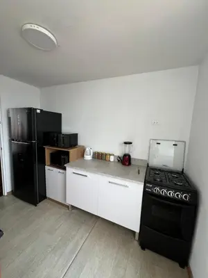 a kitchen with a stove and a black refrigerator at Departamento Prescott in Lima