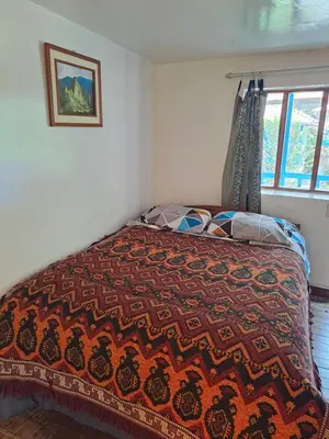 a bedroom with a bed with a colorful blanket on it at Las Portadas in Ollantaytambo