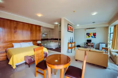 a bedroom with a bed and a living room at Grima Hotel in Huánuco