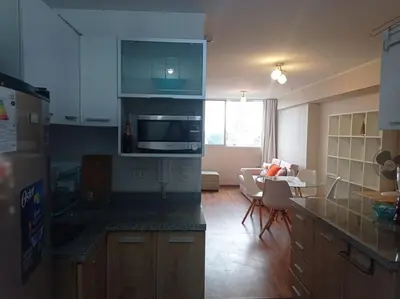 a kitchen with a counter top and a living room at Departamento en Santa Catalina in Lima