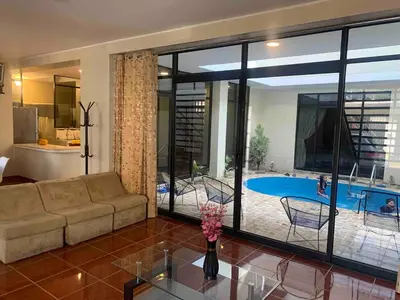 a living room with a couch and a table and a pool at Casa Hospedaje Las Lomas con piscina en La Merced in La Merced