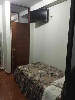 a bedroom with a bed and a wooden door at Casa Hospedaje Las Lomas con piscina en La Merced in La Merced