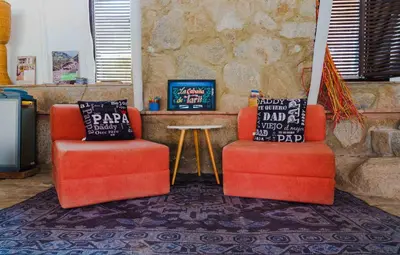 two orange chairs and a table in a room at Las Cabañas de Tarii in Cieneguilla