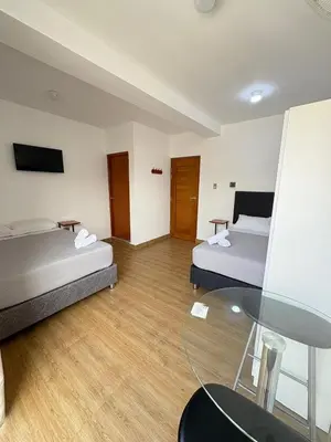 a room with two beds and a glass table at Hotel Costa Arena in Supe